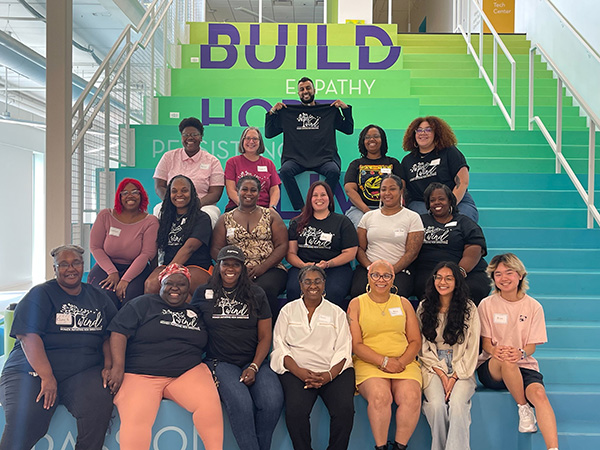 A group of women in WIND t-shirts sitting on stairs